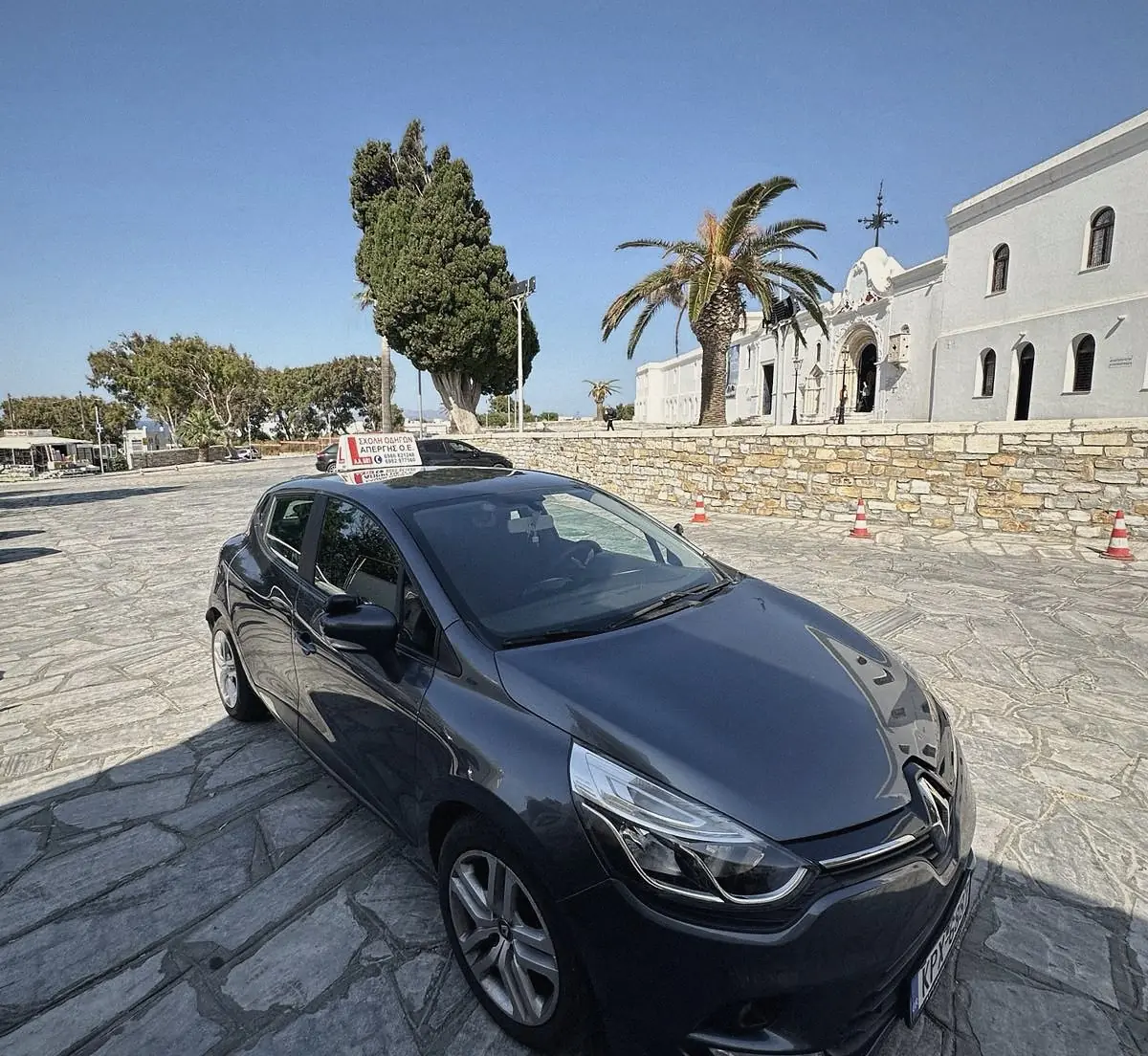 Το αυτοκίνητο της σχολής μπροστά σε εκκλησία της Τήνου